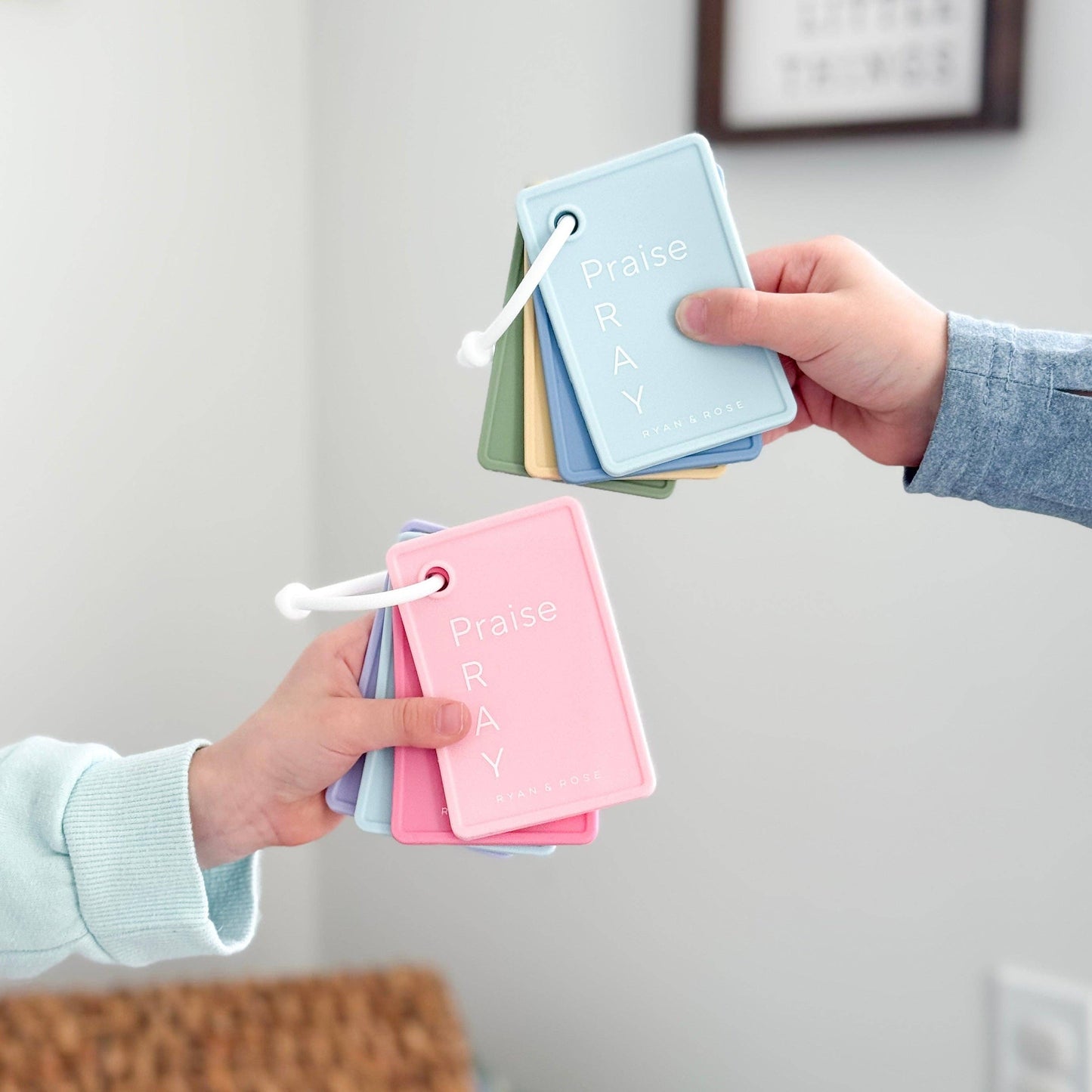 Two hands holding color swatch books with pastel colors on a neutral background