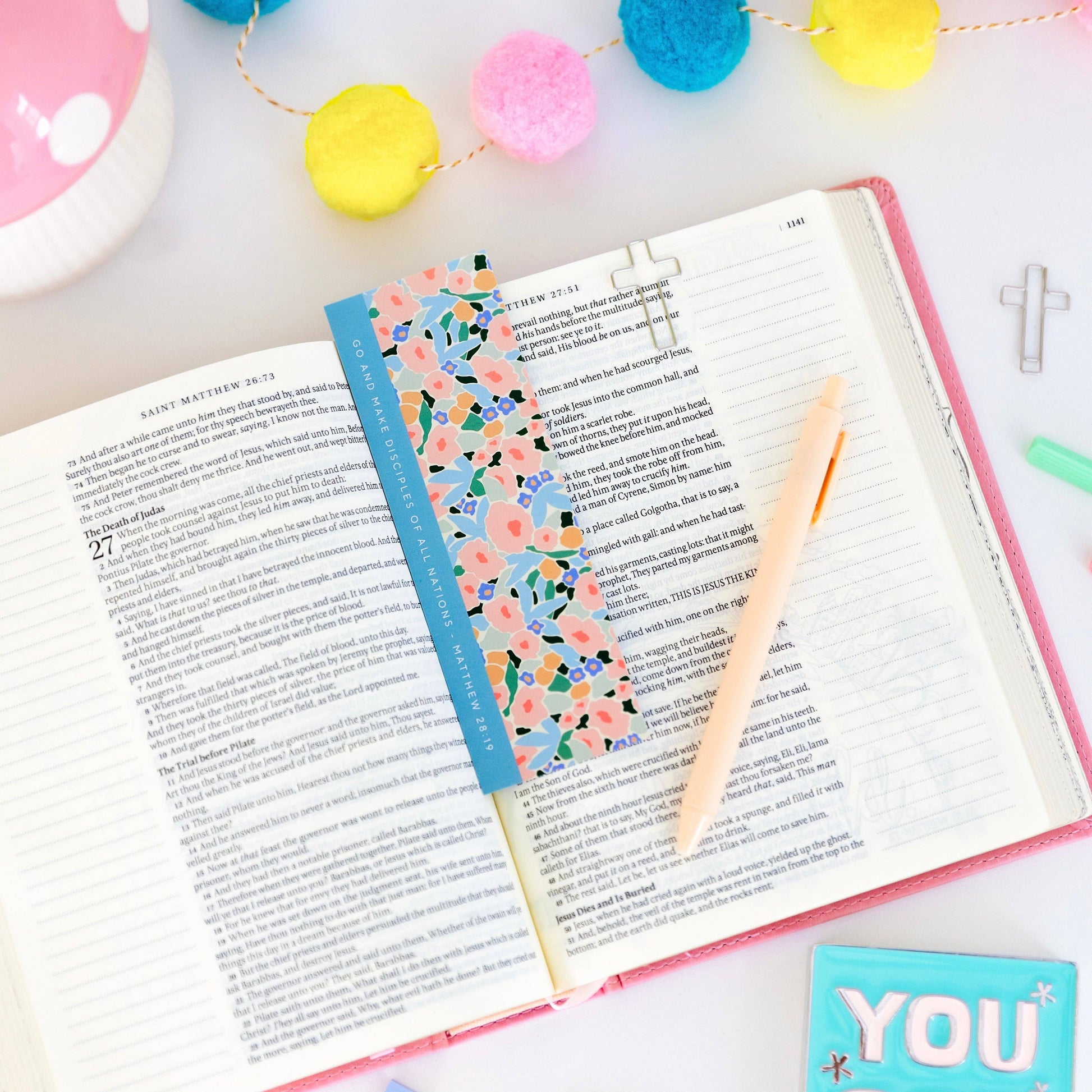 Open book with a colorful bookmark on a white surface with decorative items.