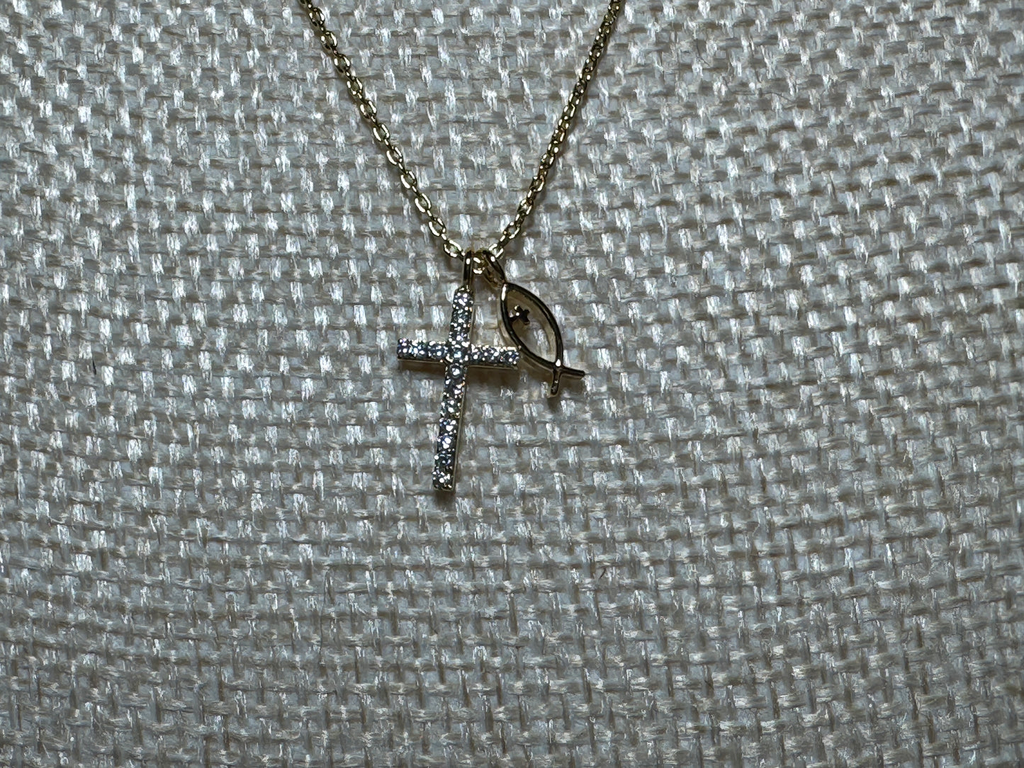 Gold cross necklace with eye design on a textured gray background