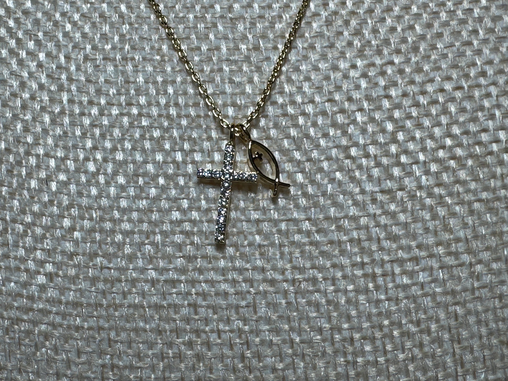 Gold cross necklace with eye design on a textured gray background