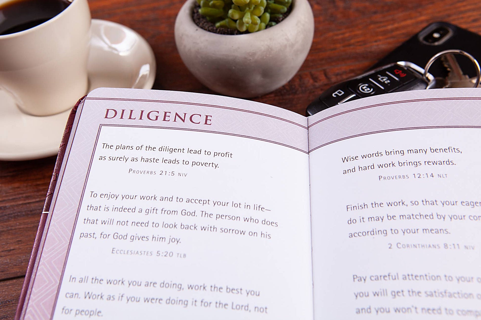 Open book with text on a wooden table with a cup of coffee and plant.