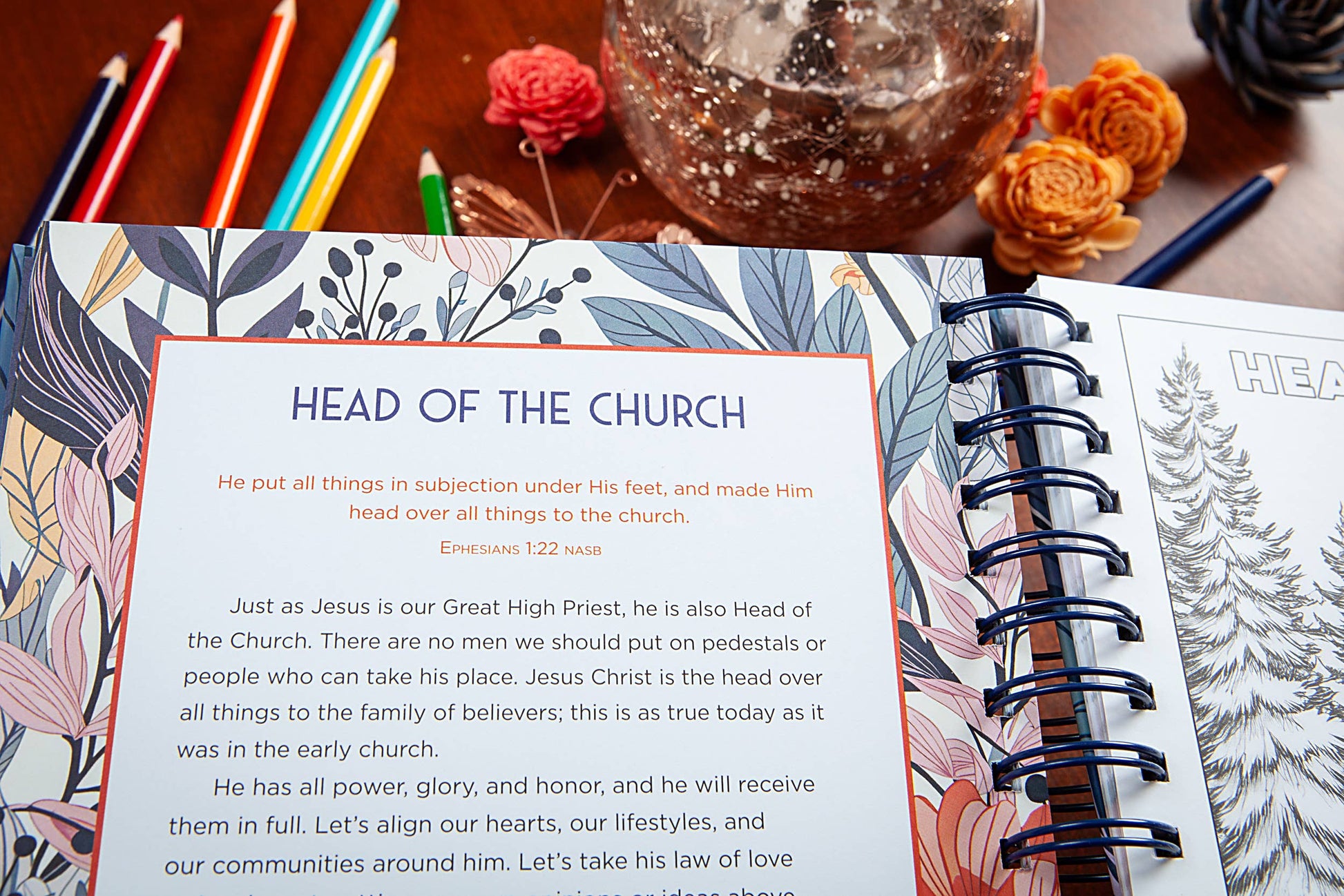 Coloring book open to a page with 'Lord of Lords' text and illustrations on a wooden surface with coloring pencils.