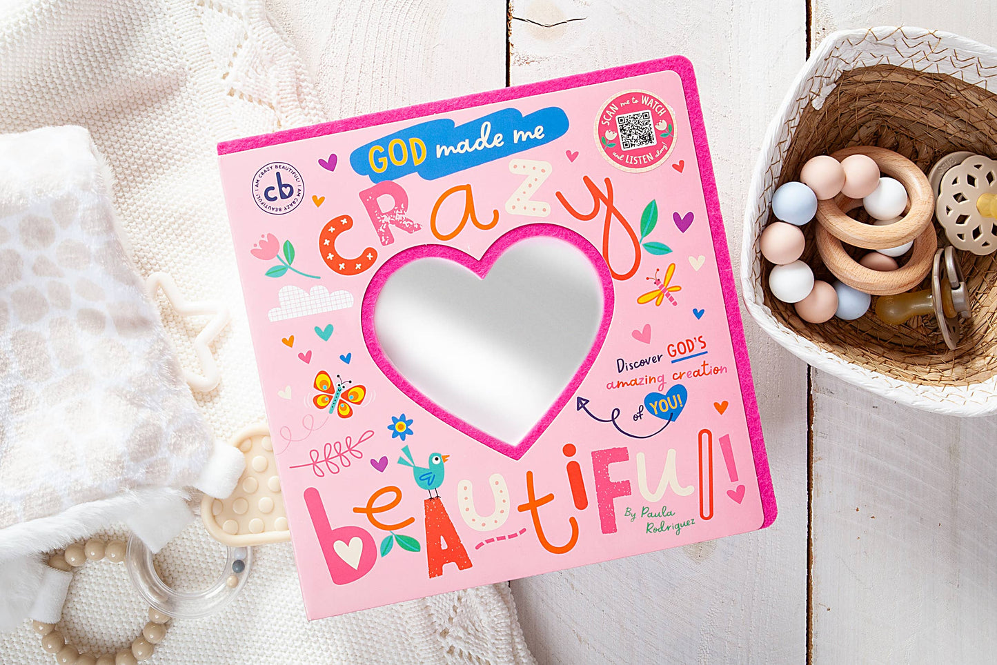 Children's book titled 'God Made Me Crazy Little Beautiful' on a wooden surface with toys.