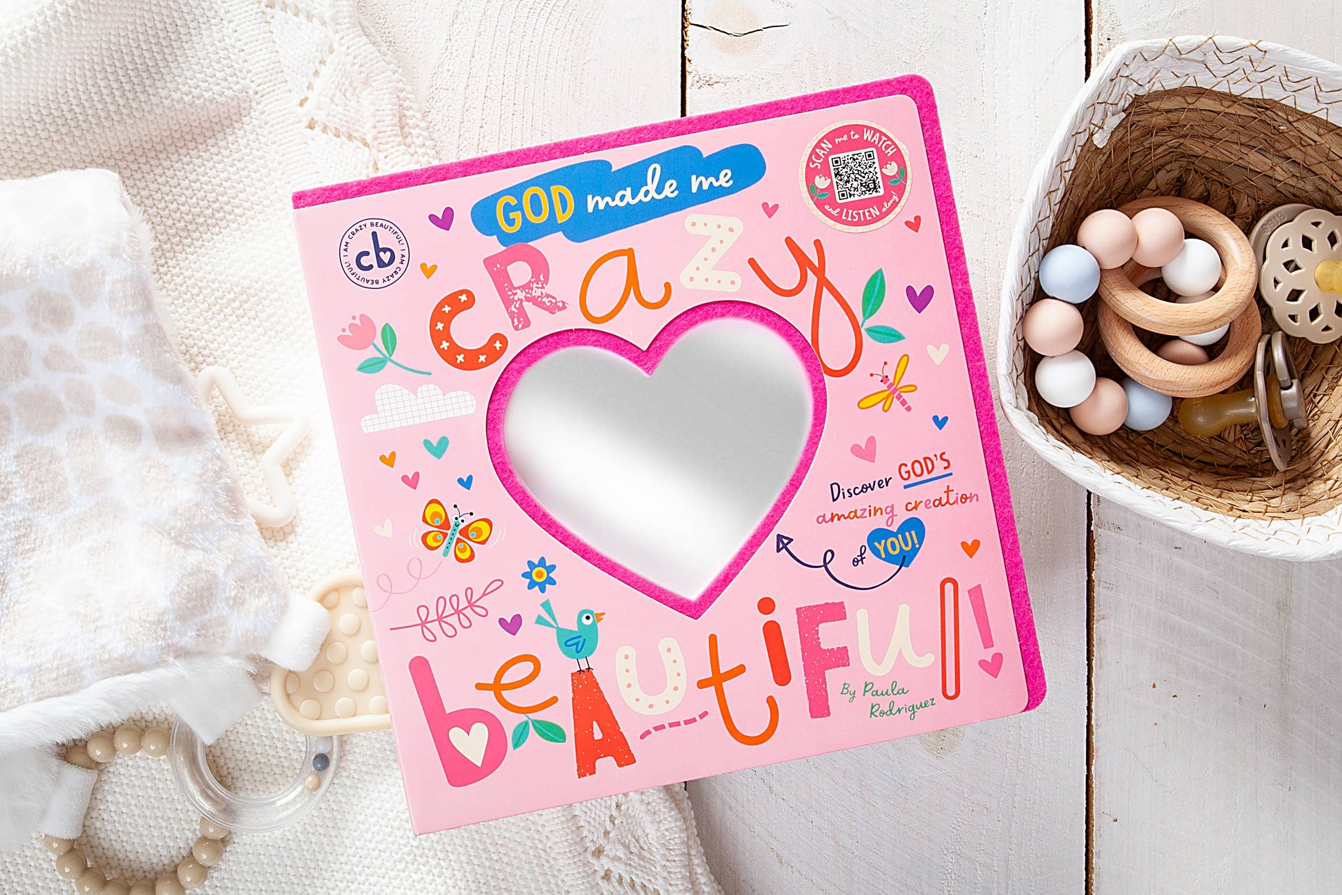 Children's book titled 'God Made Me Crazy Little Beautiful' on a wooden surface with toys.