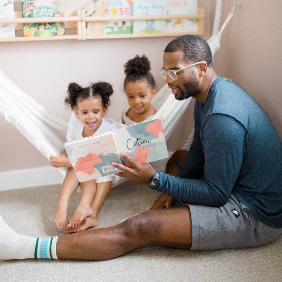 Man reading a book to two children in a cozy indoor setting