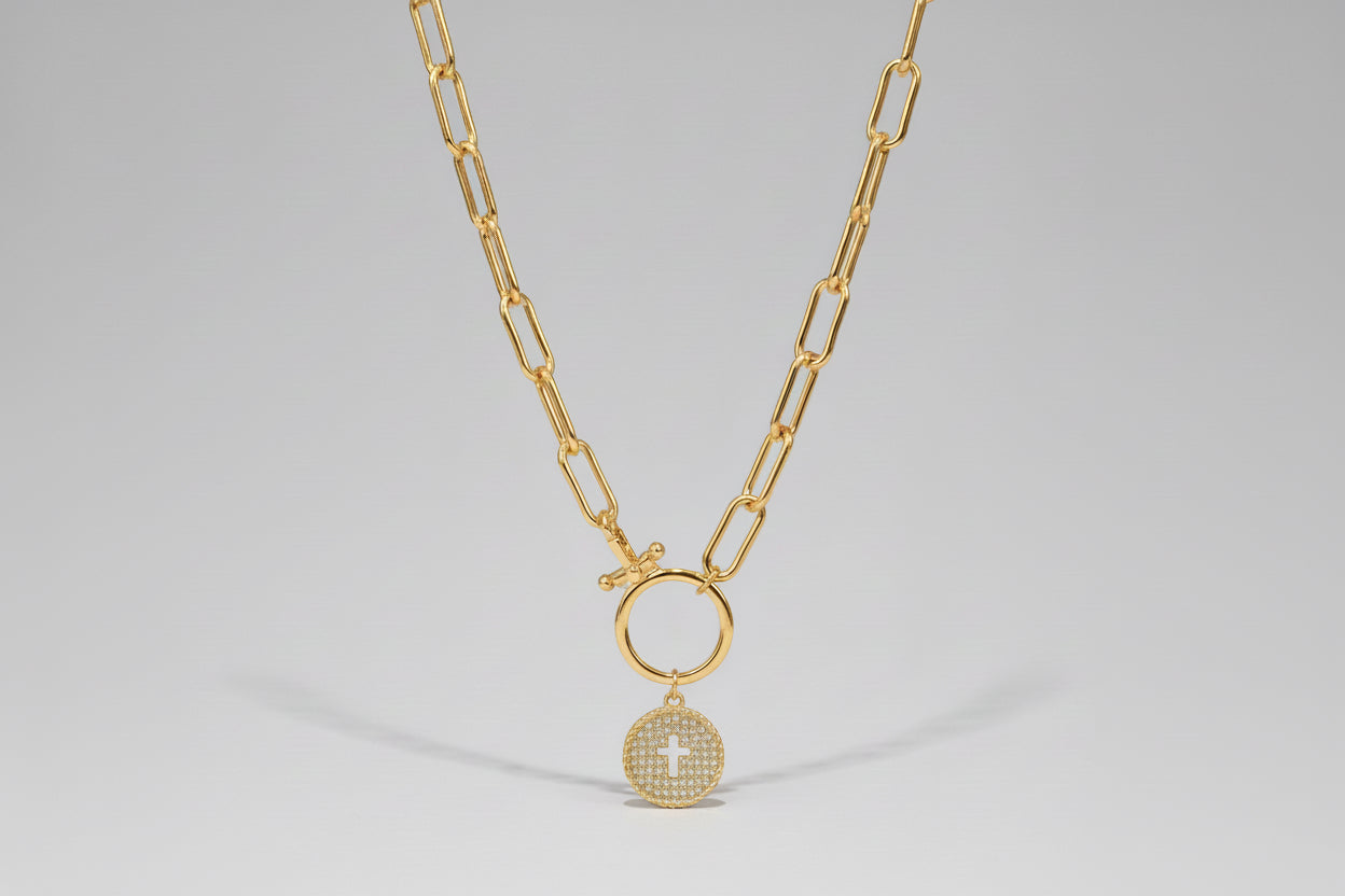 Silver necklace with a circular pendant featuring a cross on a wooden surface