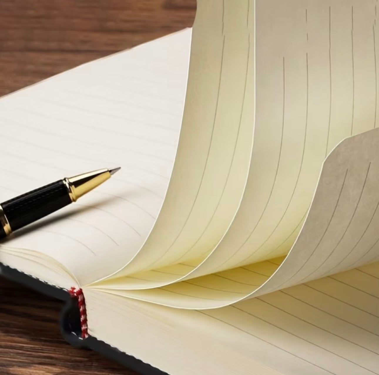 Open notebook with a pen on a wooden surface