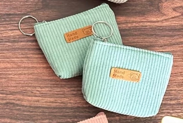 Two light green Corduroy coin purses with attached keyring and zipper closure.