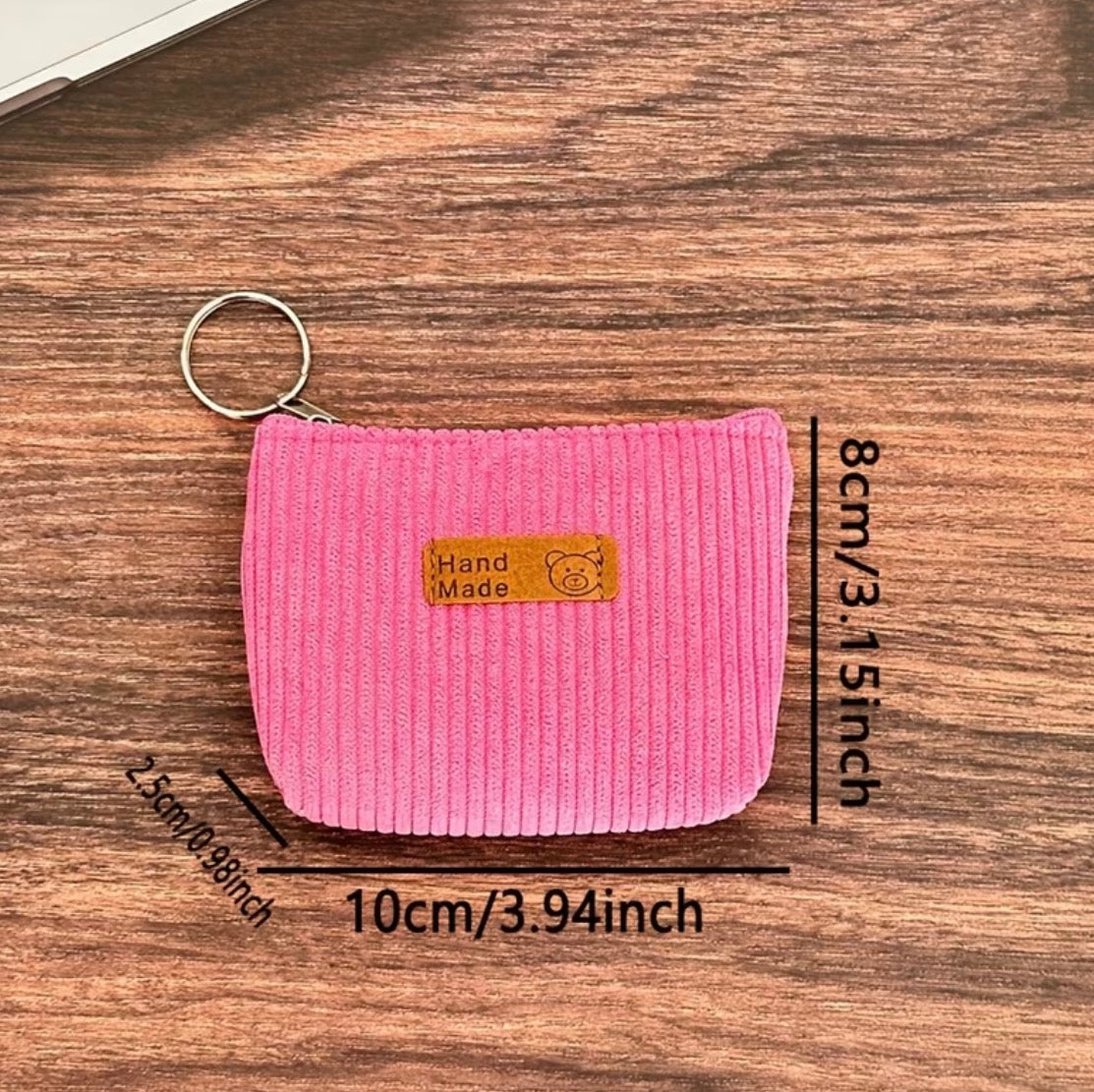 Pink corduroy coin purse with measurements on a wooden surface