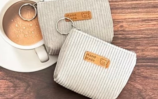 Two Corduroy light gray coin purses with attached keyring and zipper closure.