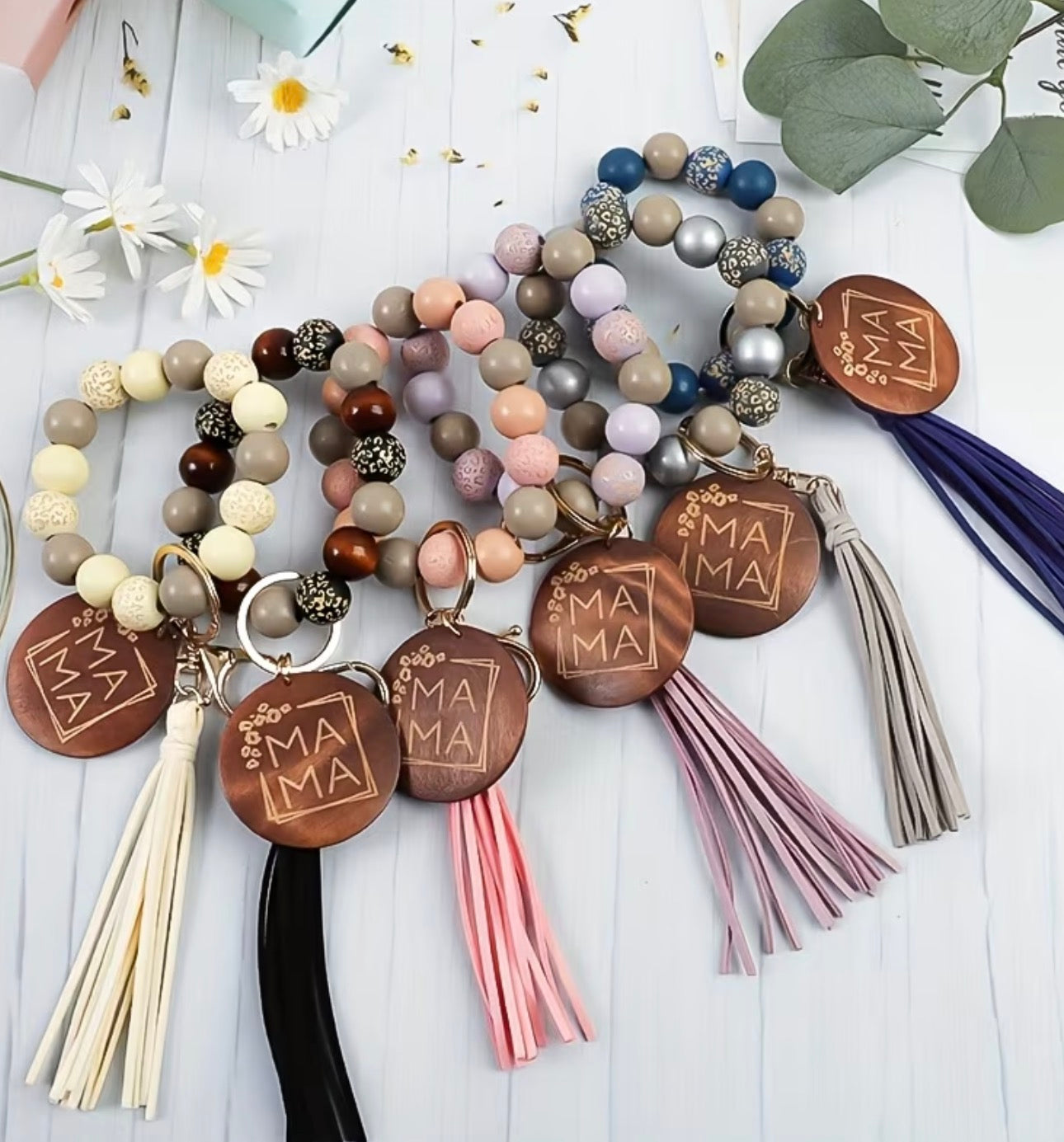 Beaded bracelets with wooden 'MAMA' charms and colorful tassels on a light wooden surface.