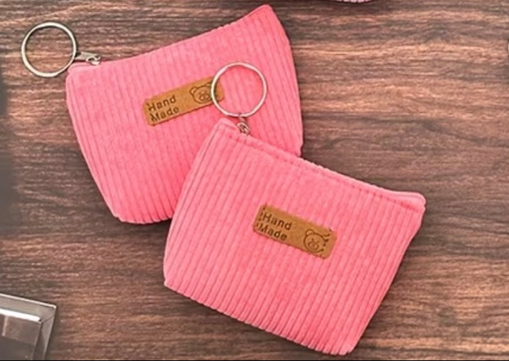 Two Corduroy pink coin purses with attached keyring and zipper closure.