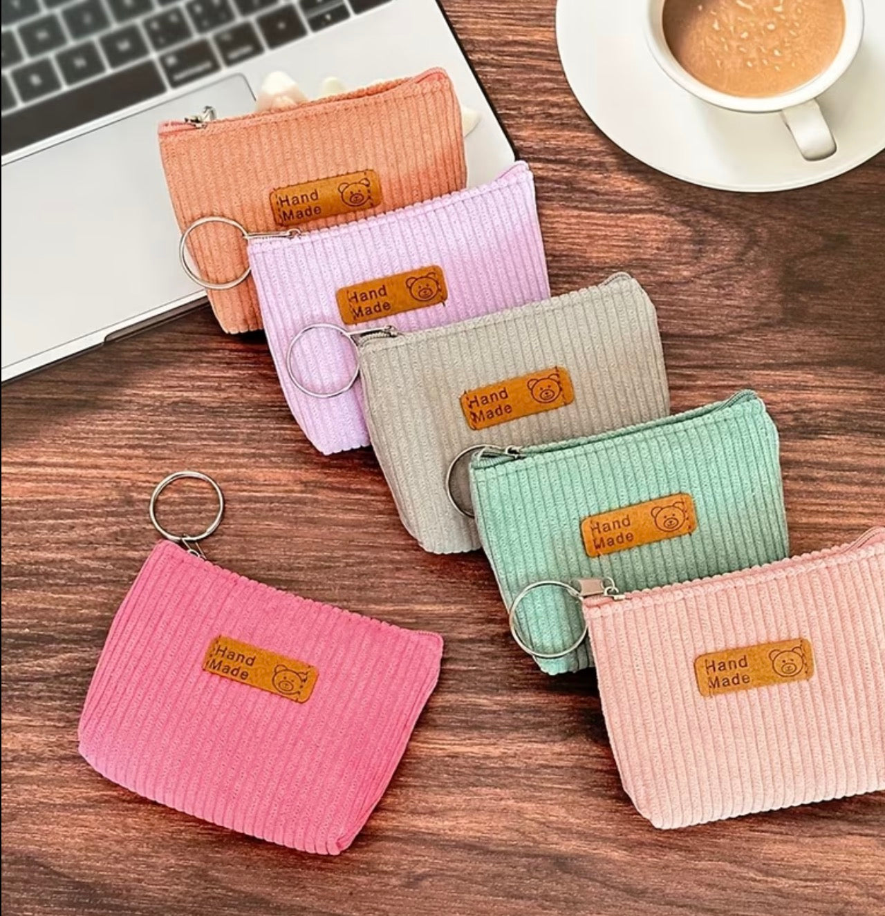 Set of colorful ribbed fabric coin purses on a wooden surface with a laptop and coffee cup in the background.