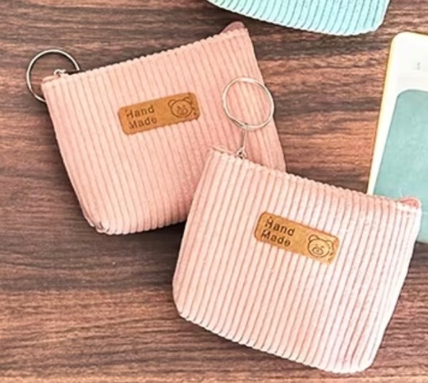 Two Corduroy light pink coin purses with attached keyring and zipper closure.