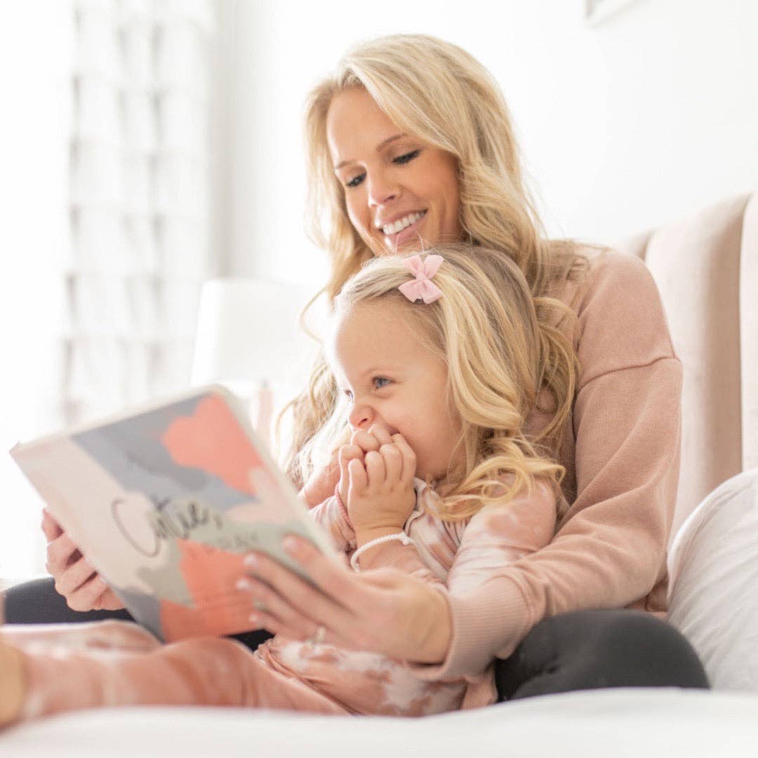 Woman reading a book to a young girl on a couch