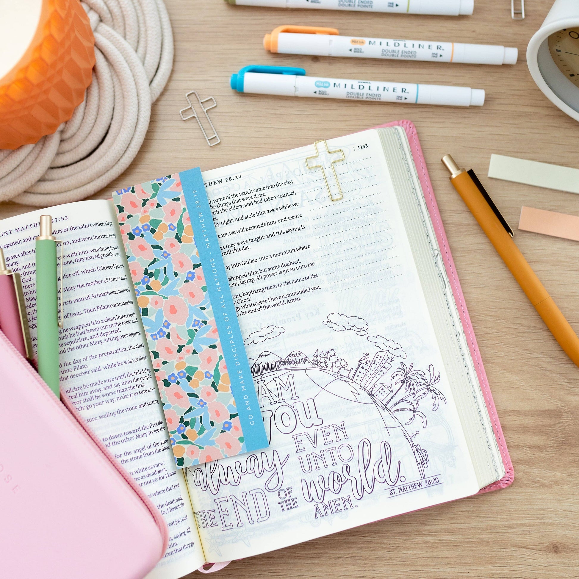 Open book with colorful bookmarks and stationery items on a wooden surface