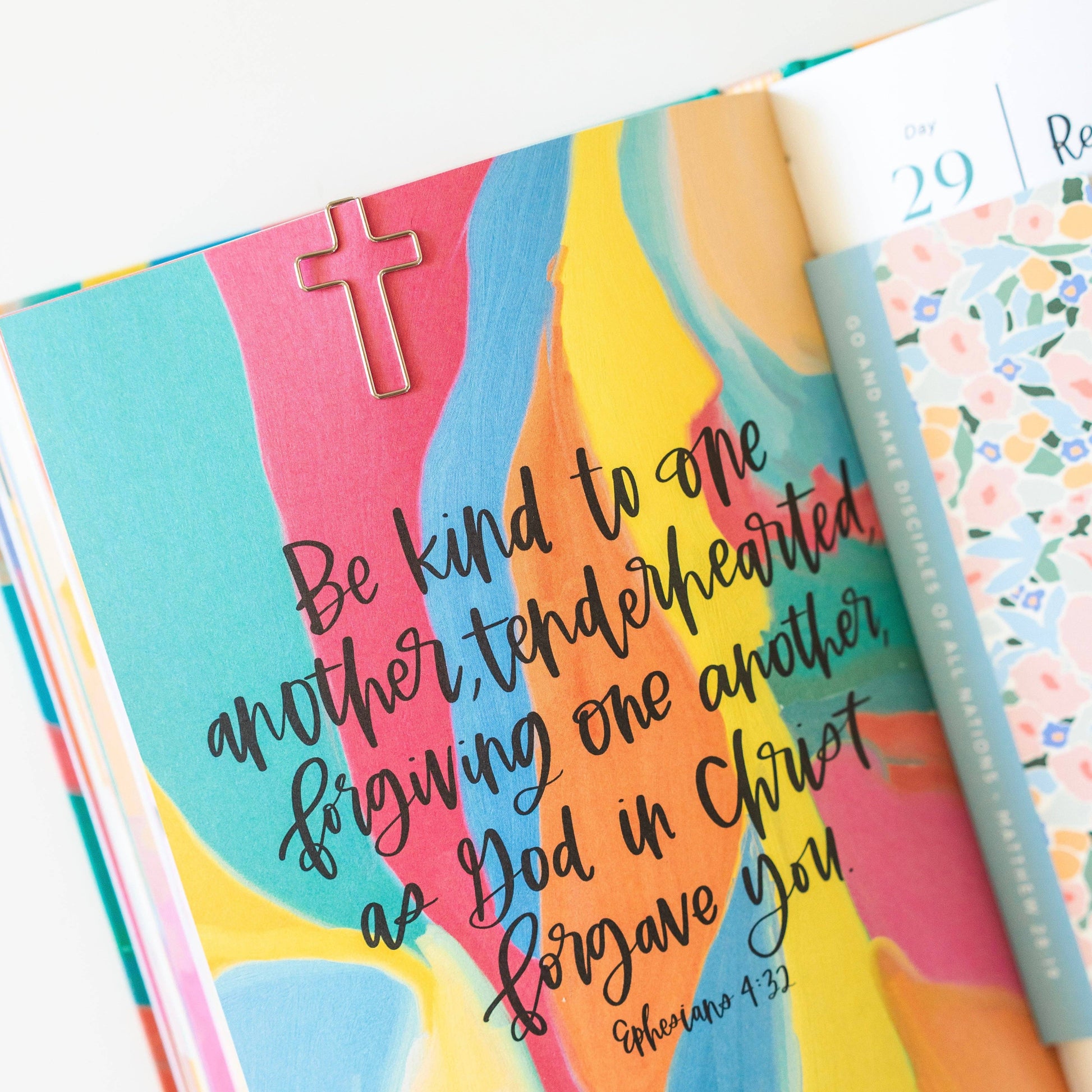 Colorful book with inspirational quote and cross clip on a white background
