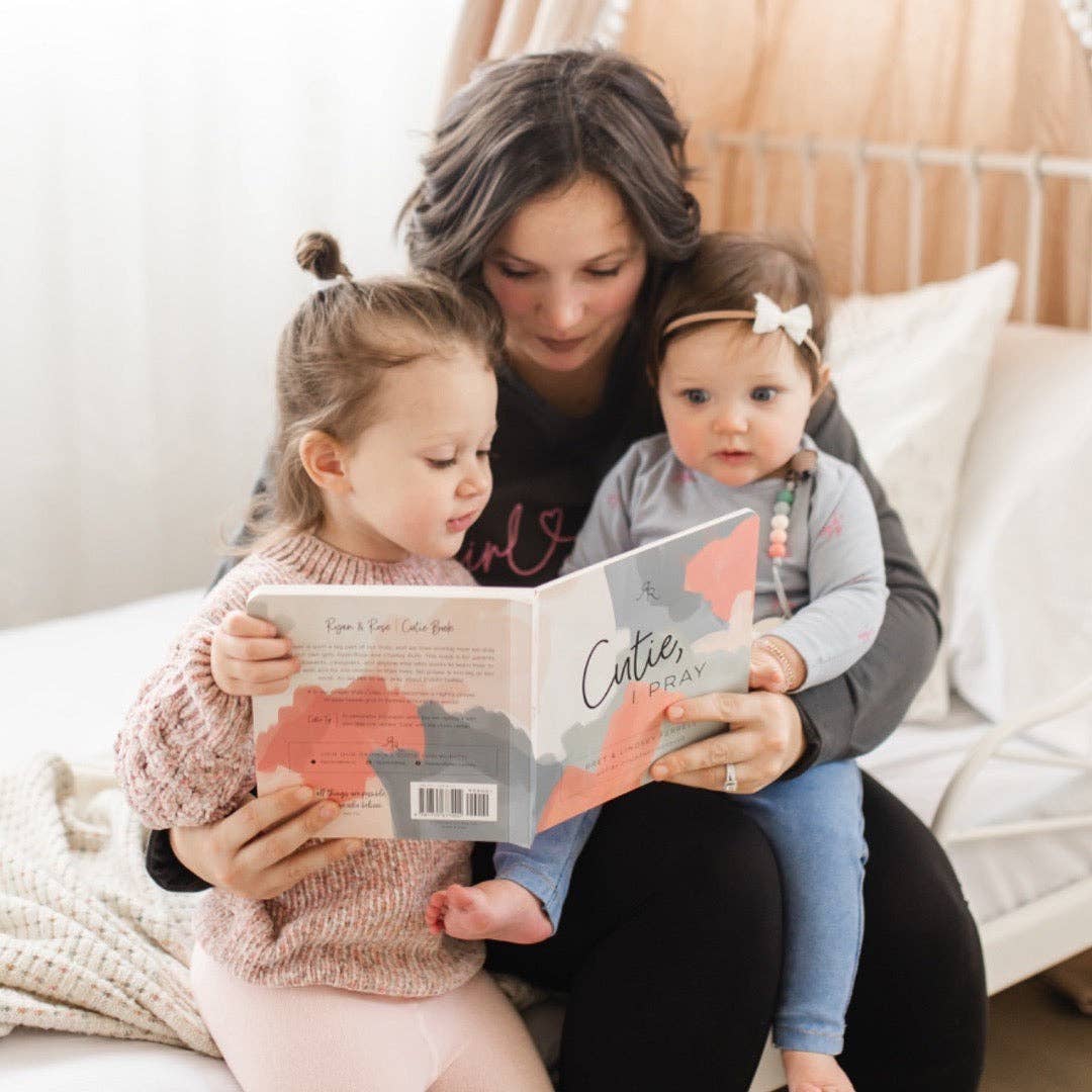 Woman reading a book to two young children on a couch.