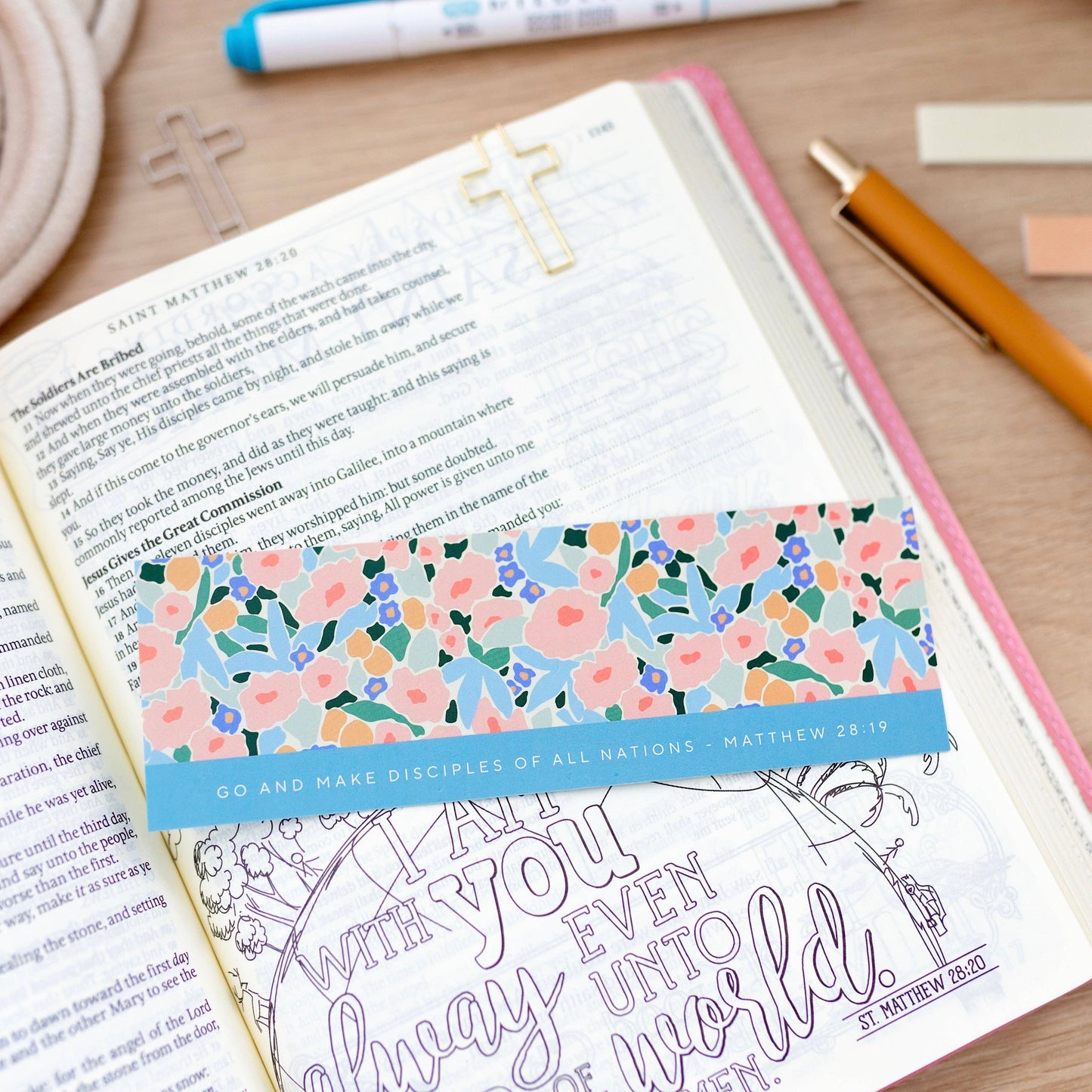 Floral bookmark in a Bible with stationery items on a wooden surface
