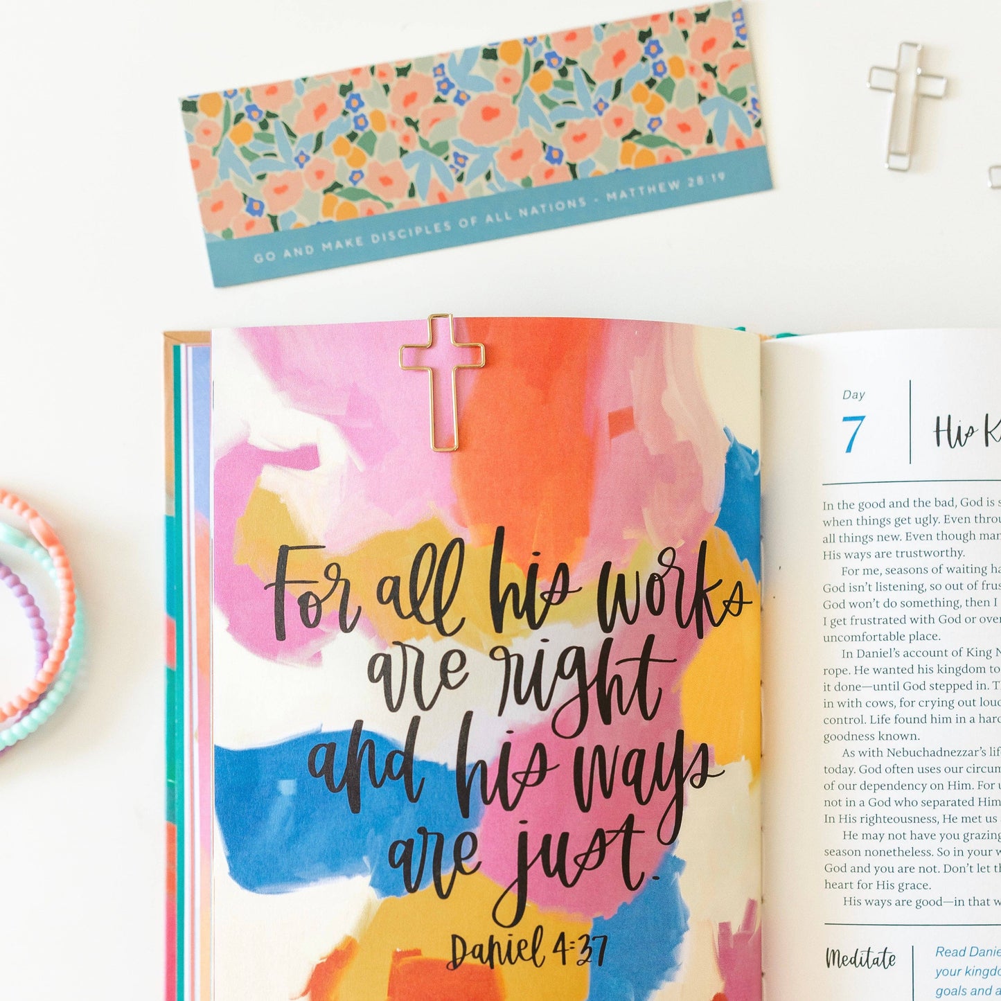 Open book with colorful design and Bible verse, featuring a floral bookmark.
